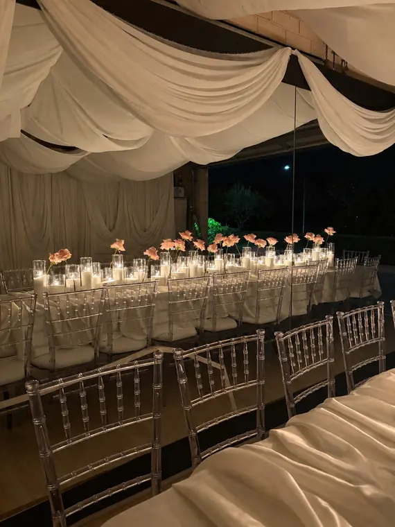Draped marquee dining table with rose and candle centrepieces